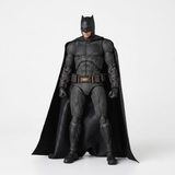 A Batman action figure or collectible statue in a full-body pose, wearing a textured black suit with a flowing black cape, standing against a plain light gray studio background.