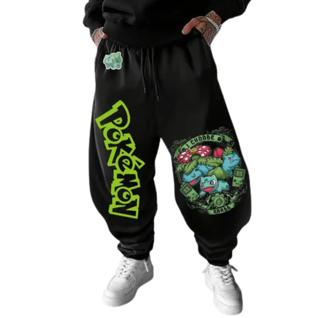 Black jogger sweatpants with a large green and yellow Pokemon logo on the left leg and a colorful Charizard graphic on the right leg, shown on a model wearing white sneakers.