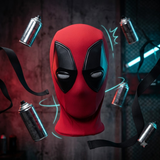 A red and black Deadpool mask centered against a dark industrial background, surrounded by floating spray paint cans and black ribbons with glowing cyan energy lines.