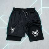 Black athletic shorts with a mesh texture, featuring a white spider logo on both legs and a black inner liner visible at the hem. The shorts are laid flat on a gray textured background with glowing neon geometric lines.