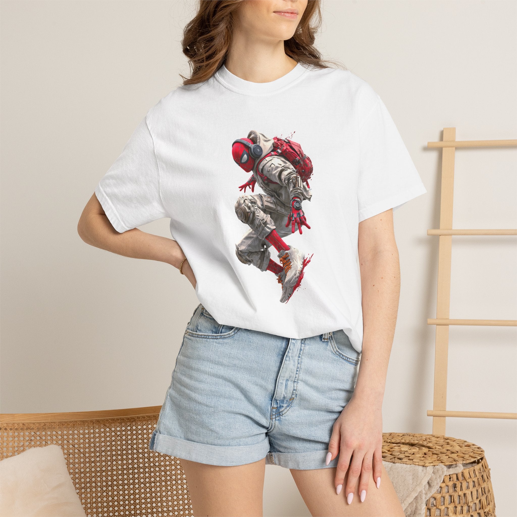 A woman wearing a white short-sleeve graphic t-shirt with a detailed print of a character in a red and gray backpack, paired with light blue denim shorts, standing in a minimalist indoor setting.