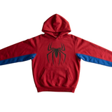 A red pullover hoodie with blue sleeve stripes and a black spider logo on the chest, laid flat on a light wood background.