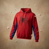 A red pullover hoodie with a large black spider logo on the chest and blue color-blocked panels on the sleeves, shown floating against a textured beige background with small white flower-like decorations.