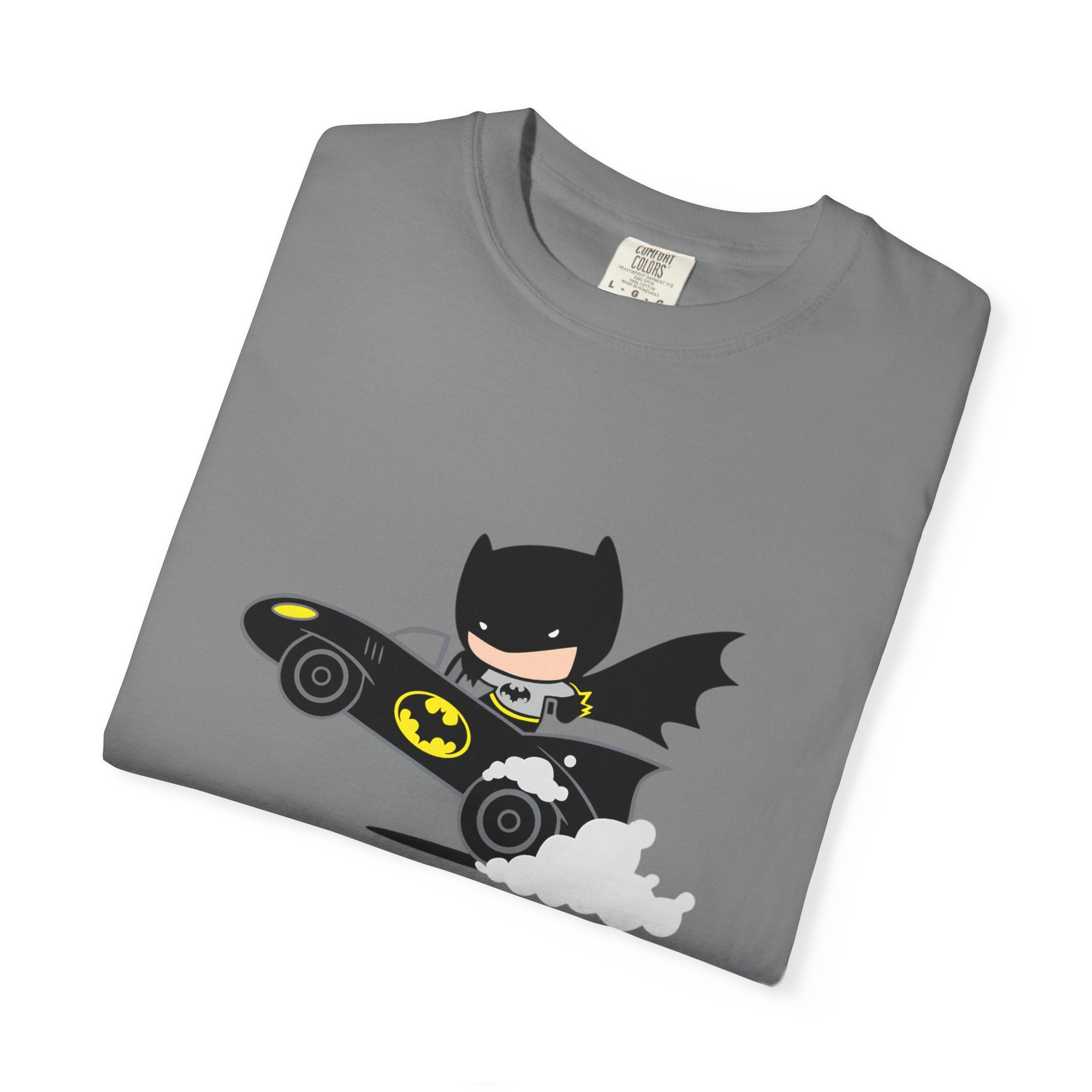 A folded gray crewneck t-shirt featuring a cartoon graphic of Batman riding his black and yellow Batmobile with white smoke, displayed on a clean white background.