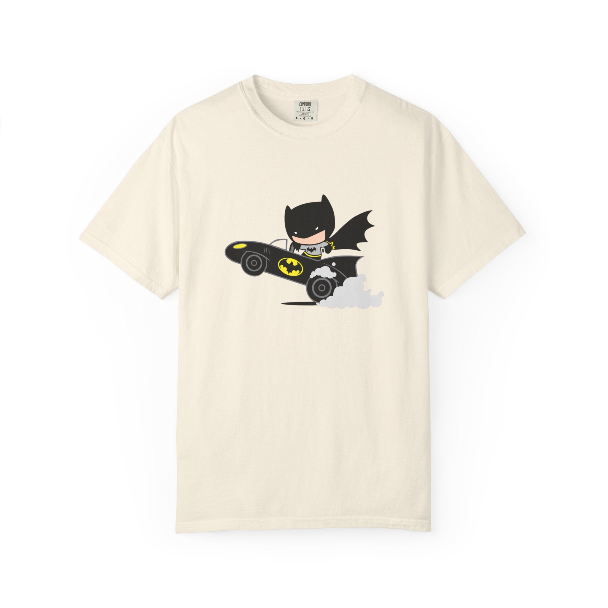 An off-white short-sleeve crewneck t-shirt featuring a cartoon graphic of Batman driving a black Batmobile with yellow accents and gray smoke, displayed on a clean white background.