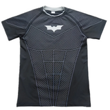 A short-sleeve athletic compression shirt styled like Batman's armor, featuring a black and dark gray honeycomb pattern with a white bat symbol on the chest, shown flat on a white background.