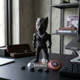 Black Panther bobblehead action figure on a clear stand with Captain America shield and extra hands on a desk in an office setting.