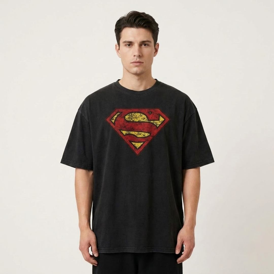 A man wearing a black t-shirt with a distressed red and yellow Superman logo on the chest, standing against a light gray background.