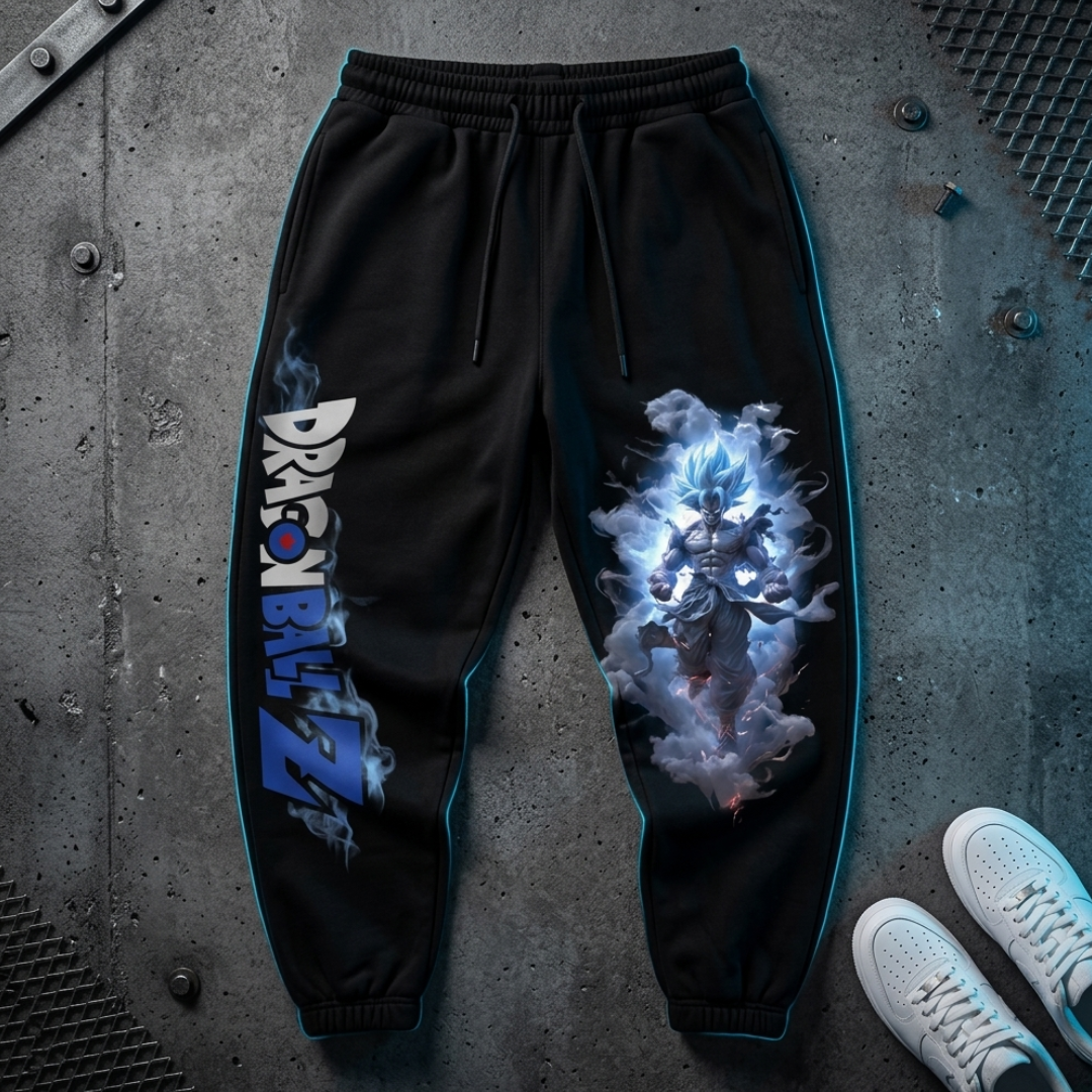 Black Dragon Ball Z sweatpants with blue side piping, featuring a large Blue Spirit character graphic on the right leg and the Dragon Ball Z logo on the left leg, shown in a flat-lay on a concrete floor with white sneakers.