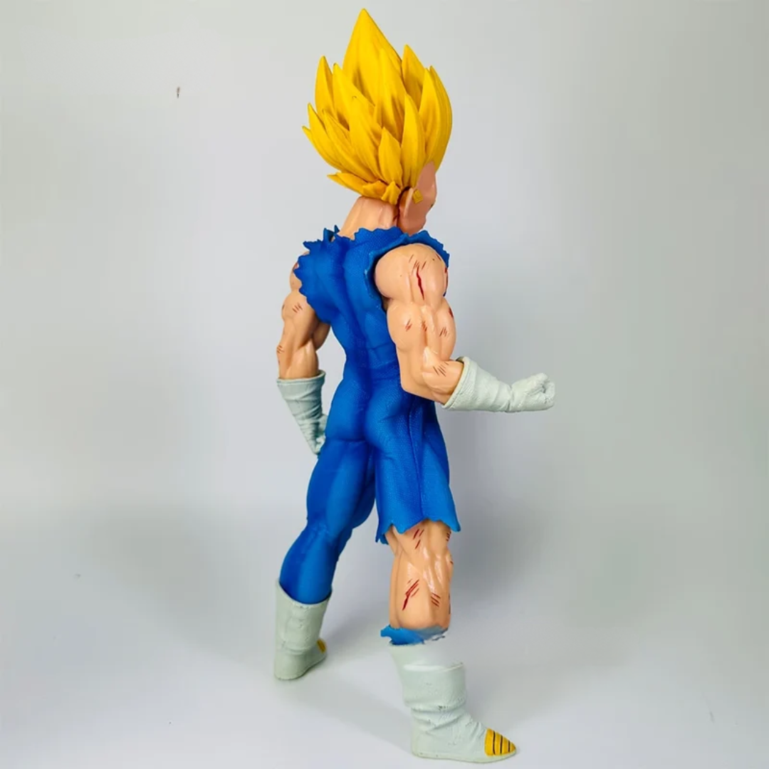 A collectible action figure of Vegeta from Dragon Ball Z, shown from a three-quarters back view. The figure features his signature spiky yellow hair, a torn blue jumpsuit, beige skin with detailed muscular definition, white gloves, and white boots with yellow tips.