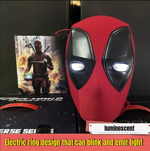 A red Deadpool-style mask with black eye shapes and glowing white circular eye areas, shown alongside its product box and a printed Deadpool card. The image includes text overlays describing the electric ring design and a luminescent effect.
