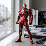 A detailed collectible action figure of Iron Man in red and gold armor stands on a windowsill with a city street view in the background, next to books.