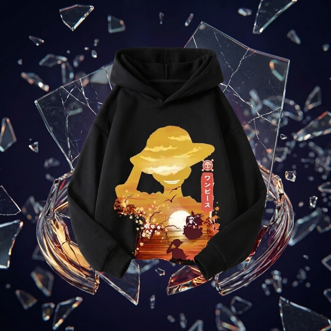 A black pullover hoodie with a large anime-style graphic on the front, featuring a golden-yellow character silhouette, a sunset scene, and red vertical text, displayed against a dark background with floating broken glass shards.