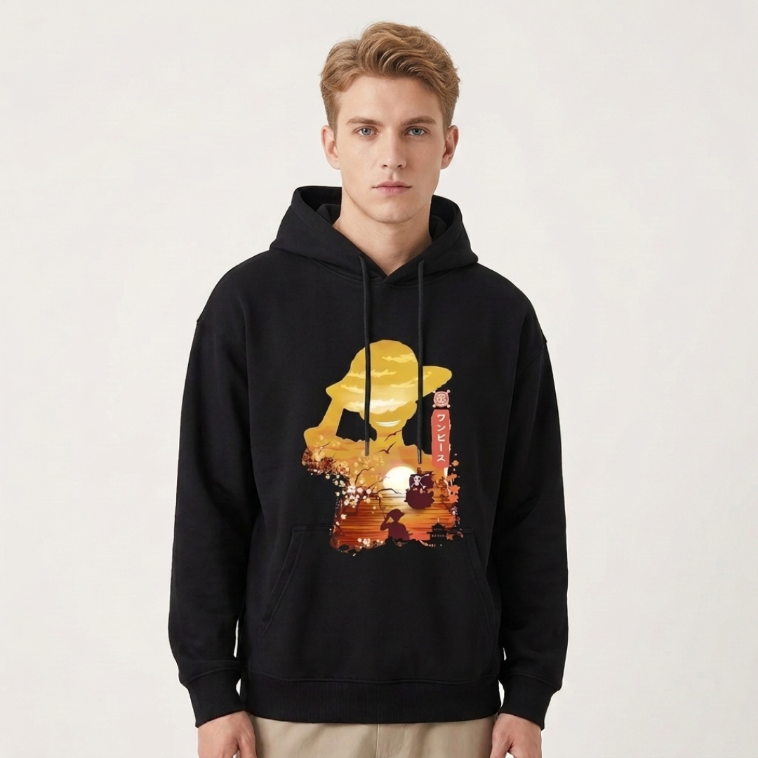 A man wearing a black pullover hoodie with a large graphic print on the front. The graphic features a stylized golden-yellow silhouette of a person in a hat against a sunset-like background with red and orange tones.